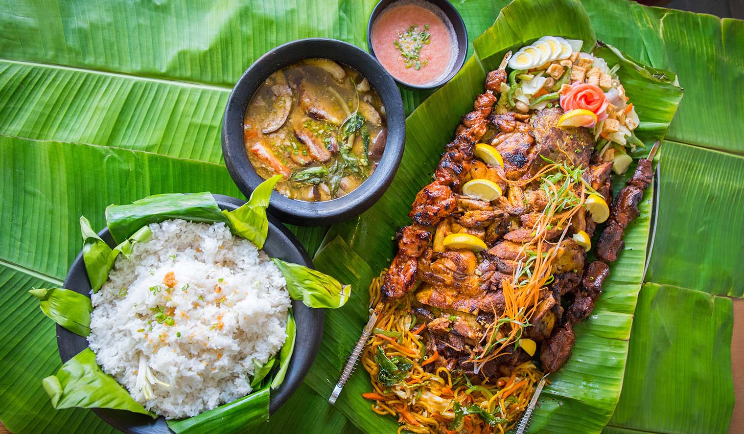 Philippinisches Essen mit Reis, Barbeque und Gemüse auf Reiseblatt ausgelegt